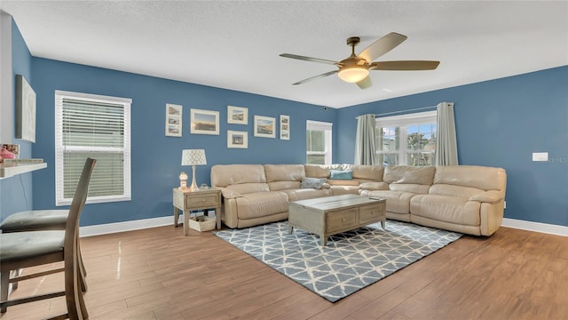 living room featuring ceiling fan, light hardwood / wood-style flooring, and a textured ceiling