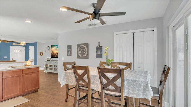 dining space with ceiling fan and light wood-type flooring