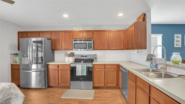 kitchen with stainless steel appliances, sink, and light hardwood / wood-style flooring