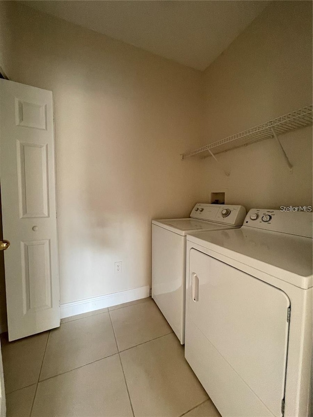 clothes washing area with light tile patterned floors and washer and clothes dryer