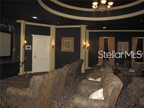 carpeted home theater room with ornamental molding and a raised ceiling