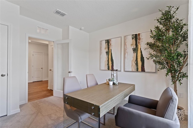 dining room featuring light colored carpet and a textured ceiling