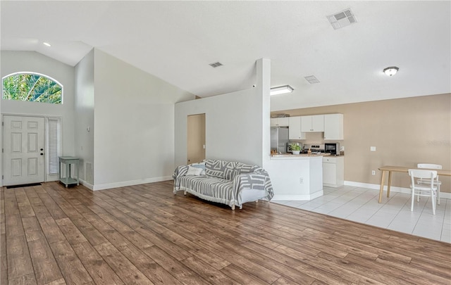 foyer entrance featuring high vaulted ceiling and light wood-type flooring