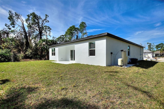 rear view of house with central AC, a patio area, and a lawn