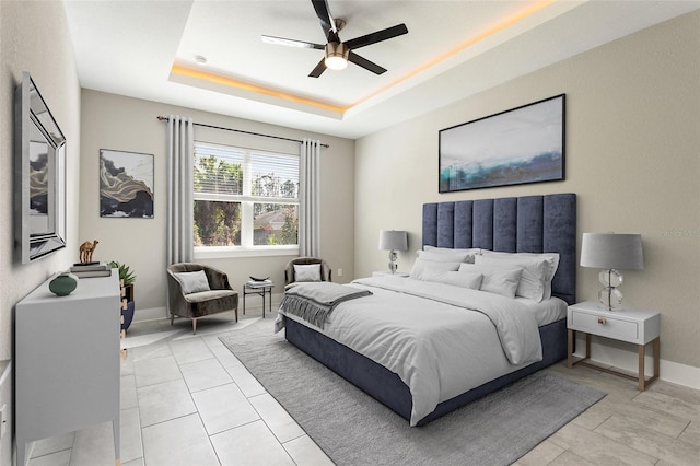 bedroom featuring a raised ceiling, light tile patterned floors, and ceiling fan