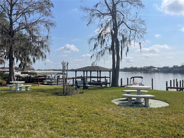 dock area featuring a gazebo, a water view, and a lawn