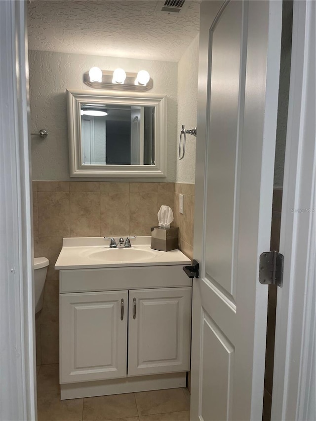 bathroom with tile patterned floors, vanity, toilet, and tile walls