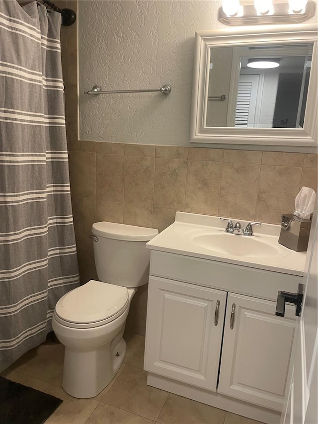 bathroom featuring tile patterned floors, toilet, vanity, and tile walls