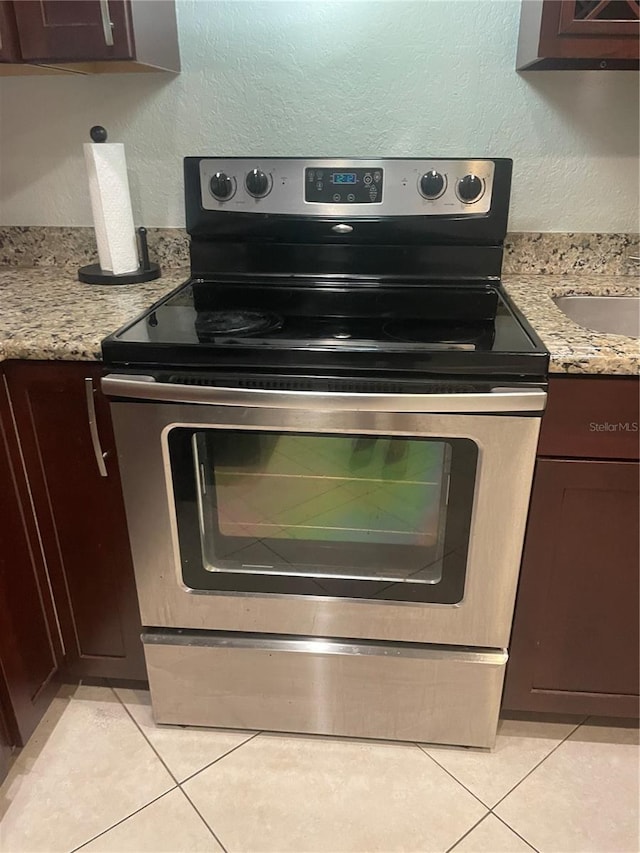 details featuring stainless steel range with electric stovetop, light stone counters, and dark brown cabinetry