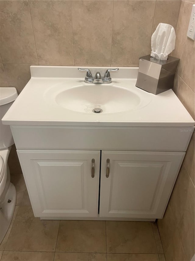 bathroom with tile patterned flooring, vanity, tile walls, and toilet