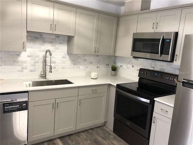 kitchen with appliances with stainless steel finishes, dark hardwood / wood-style floors, sink, and decorative backsplash