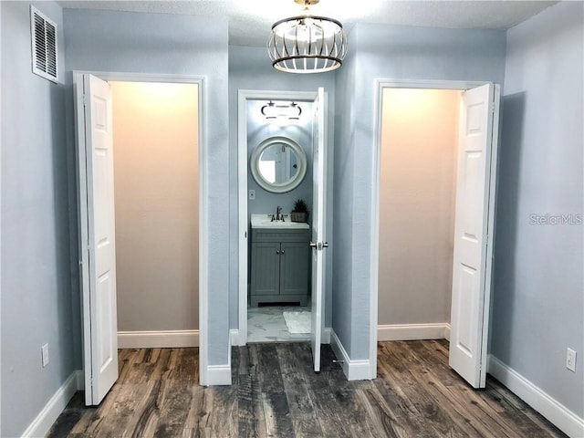 interior space featuring sink, a notable chandelier, and dark wood-type flooring