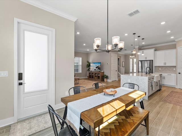 dining area featuring crown molding, a notable chandelier, and light wood-type flooring