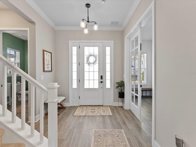 foyer entrance featuring a notable chandelier, crown molding, and light hardwood / wood-style flooring