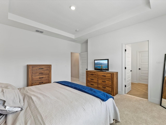 bedroom with a raised ceiling and light carpet