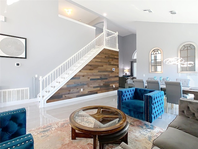 living area with stairs, a high ceiling, wood walls, and visible vents