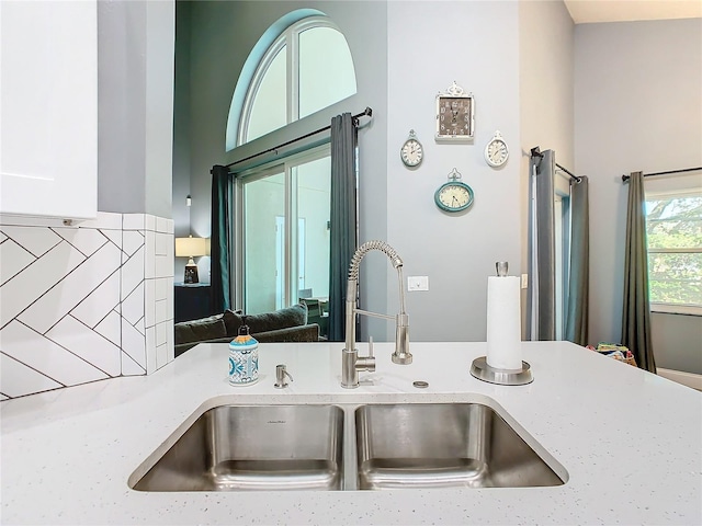 interior details with light stone counters, backsplash, and a sink