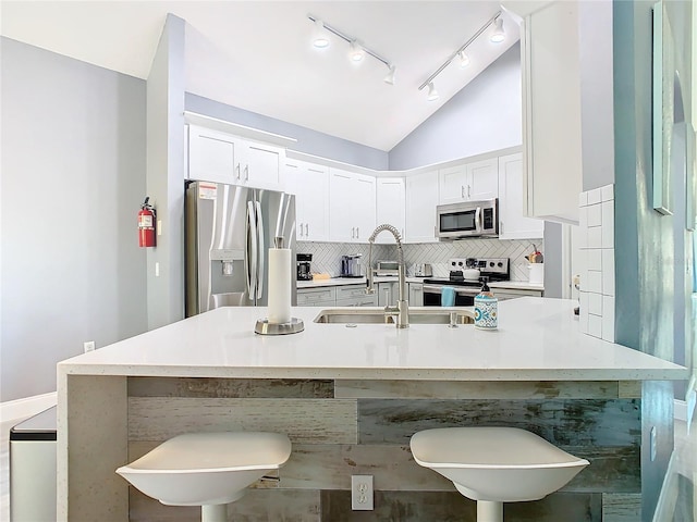 kitchen with appliances with stainless steel finishes, light countertops, a kitchen bar, and white cabinetry