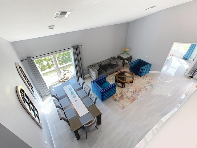 living area with vaulted ceiling, visible vents, and baseboards