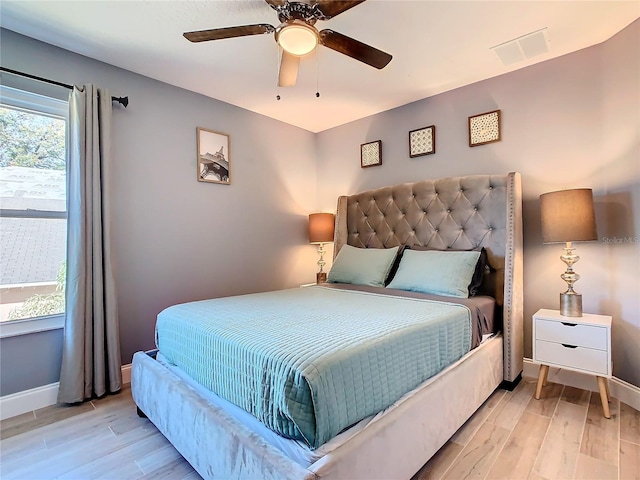 bedroom with ceiling fan, light wood finished floors, visible vents, and baseboards