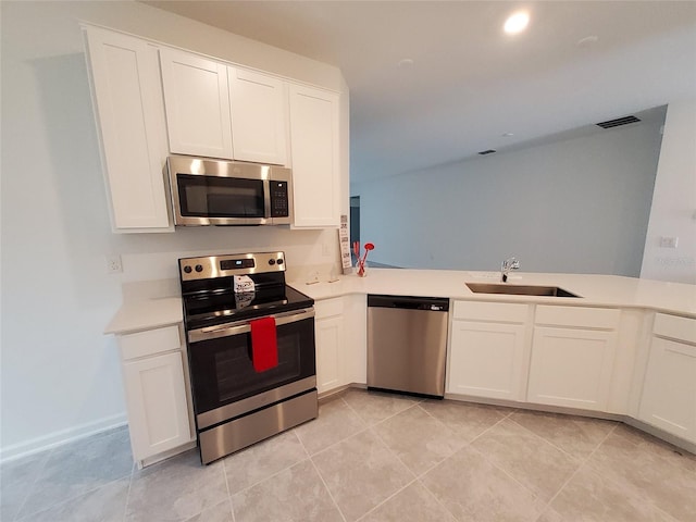 kitchen with sink, light tile patterned floors, stainless steel appliances, white cabinets, and kitchen peninsula