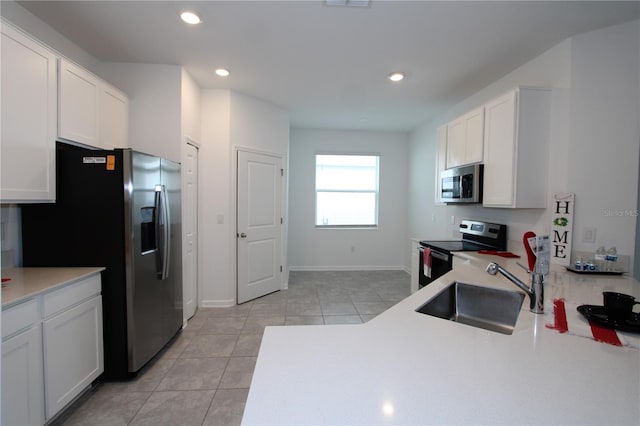 kitchen with a sink, stainless steel appliances, white cabinetry, and light tile patterned floors