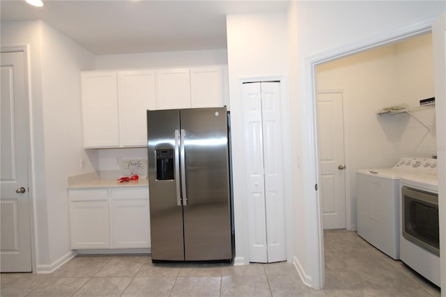 kitchen with light countertops, light tile patterned floors, washer and dryer, white cabinets, and stainless steel fridge