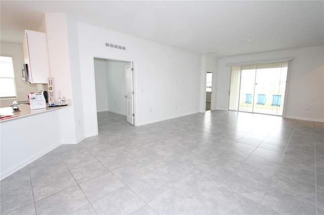 unfurnished room featuring a healthy amount of sunlight, visible vents, and baseboards