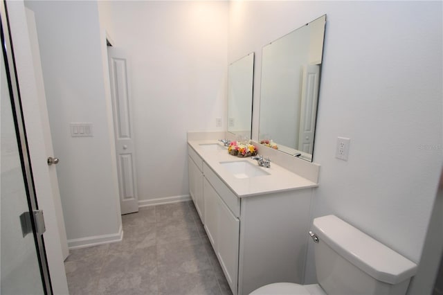 bathroom with double vanity, toilet, baseboards, and a sink