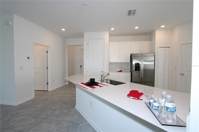 kitchen with visible vents, a sink, recessed lighting, stainless steel fridge, and white cabinets