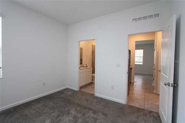 unfurnished bedroom with tile patterned flooring, visible vents, baseboards, and carpet