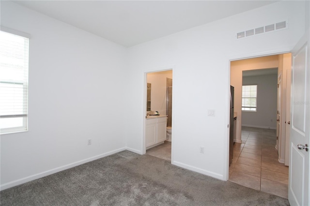 unfurnished bedroom featuring light carpet, visible vents, baseboards, and light tile patterned floors