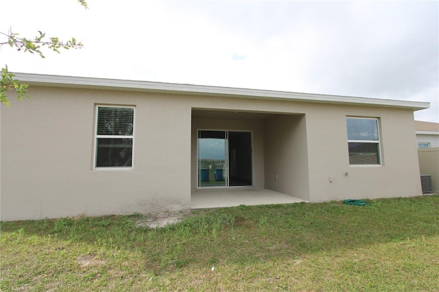 back of property with stucco siding and a lawn