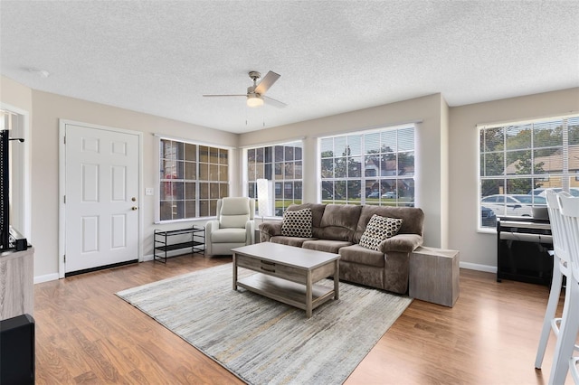 living room with ceiling fan, a textured ceiling, and light hardwood / wood-style floors