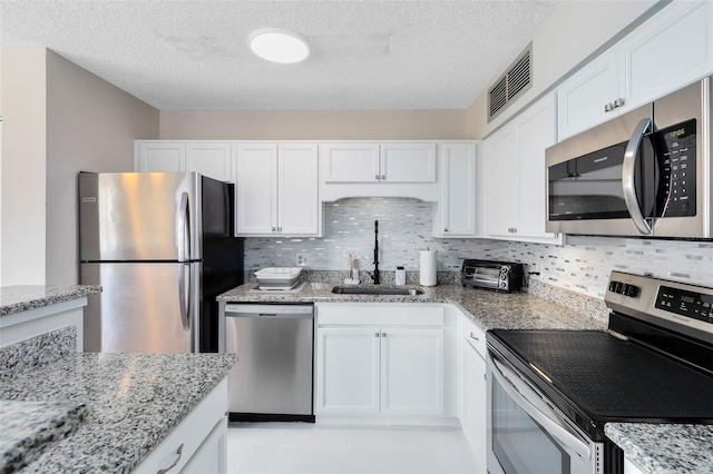 kitchen with white cabinetry, sink, light stone counters, and appliances with stainless steel finishes