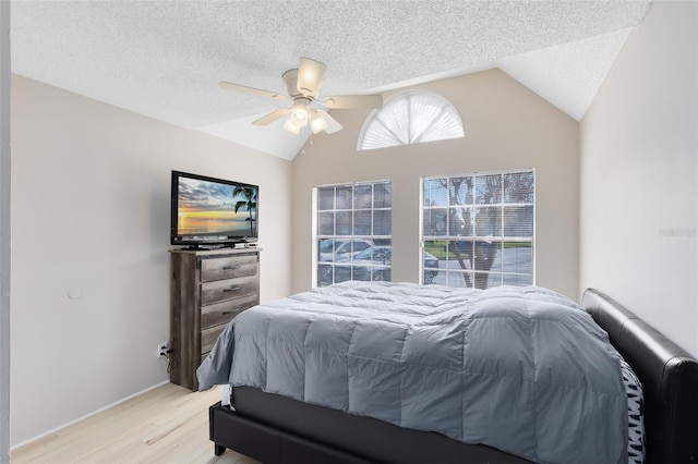 bedroom featuring ceiling fan, vaulted ceiling, light hardwood / wood-style flooring, and a textured ceiling