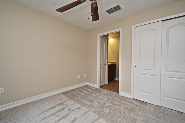 unfurnished bedroom with ensuite bathroom, light carpet, a textured ceiling, and a closet