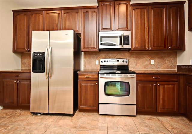 kitchen with stainless steel appliances, backsplash, and dark stone counters