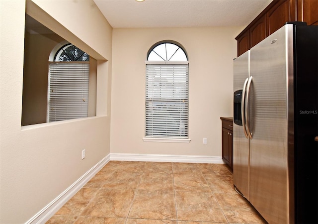 kitchen featuring stainless steel fridge and dark brown cabinetry