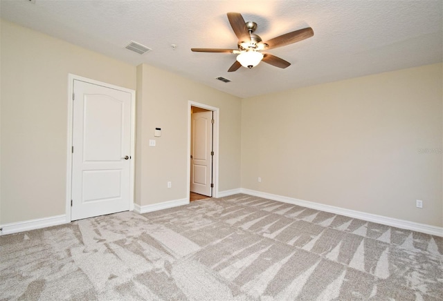 unfurnished room with ceiling fan, light colored carpet, and a textured ceiling