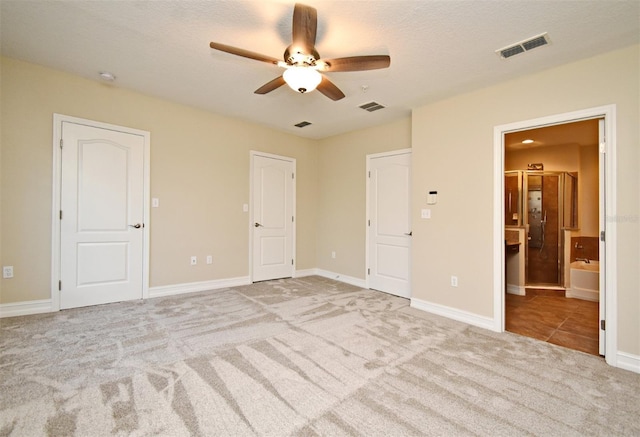 unfurnished bedroom with ceiling fan, light colored carpet, ensuite bathroom, and a textured ceiling