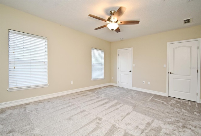 empty room featuring ceiling fan, light colored carpet, and a textured ceiling