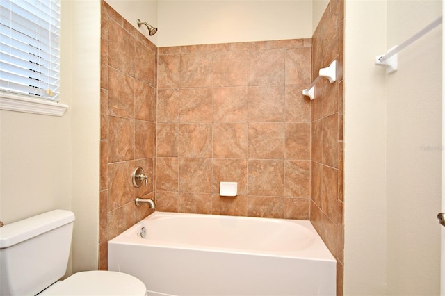 bathroom featuring tiled shower / bath combo and toilet