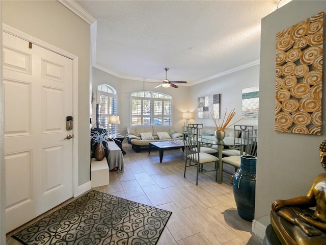 living room featuring crown molding, ceiling fan, and a textured ceiling