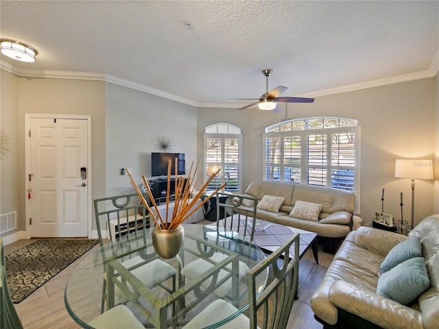 living area with a textured ceiling, visible vents, crown molding, and wood finished floors