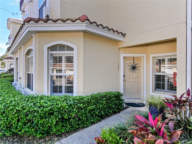 entrance to property with a tiled roof and stucco siding