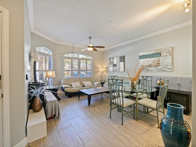 living room with a textured ceiling, ceiling fan, ornamental molding, and baseboards