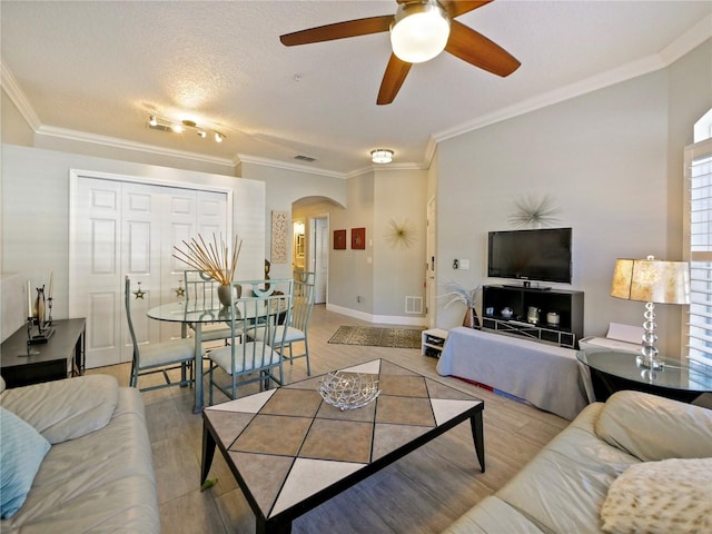 living room with arched walkways, light wood-style flooring, and crown molding