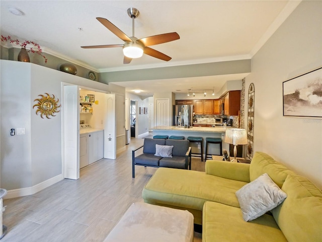 living room featuring baseboards, light wood finished floors, washer / clothes dryer, and crown molding