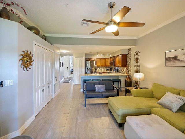 living room with visible vents, crown molding, baseboards, and ceiling fan